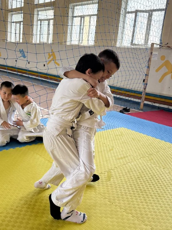 Oq kimono kiygan ikki bola sport zalida qoʻl jangi mashq qilmoqda